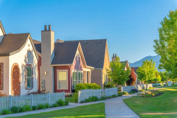 Concrete walkway at the front of houses with picket fence at Daybreak in South Jordan, Utah