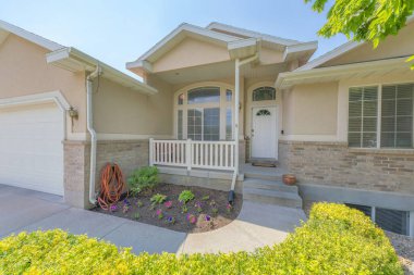 Garaj ve bodrum penceresi olan bej renkli bir ev.