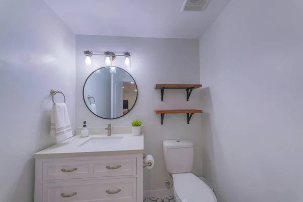 Small bathroom interior with wooden shelves and framed oval mirror — Stock Photo, Image