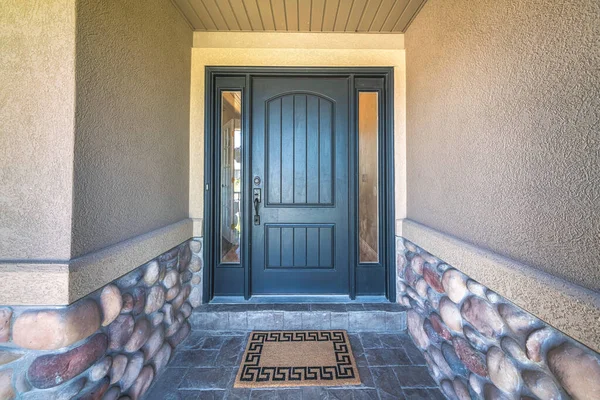 Black front door with two side panels and brown doormat