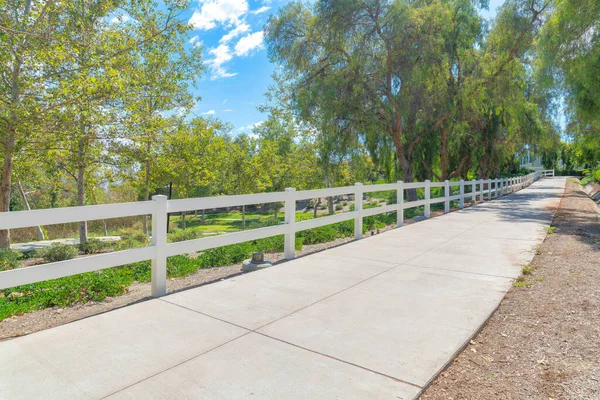 Piccolo sentiero in cemento con barriera bianca e alberi a Ladera Ranch nel sud della California — Foto Stock