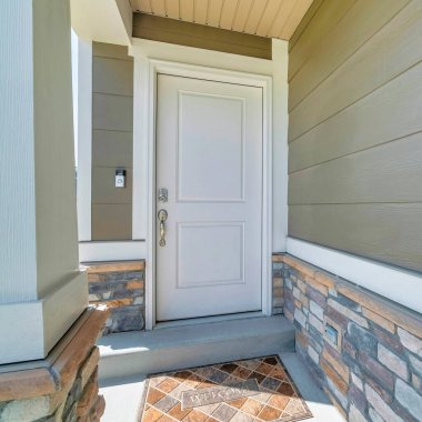 Beyaz kapısı ve paspası olan kare ev girişi.