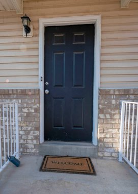 Metal parmaklıkları ve beton kapı merdivenleri olan bir evin verandası.