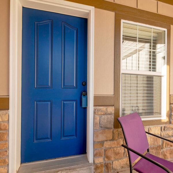 Square Exterior of a house with blue front door and purple armchairs and table