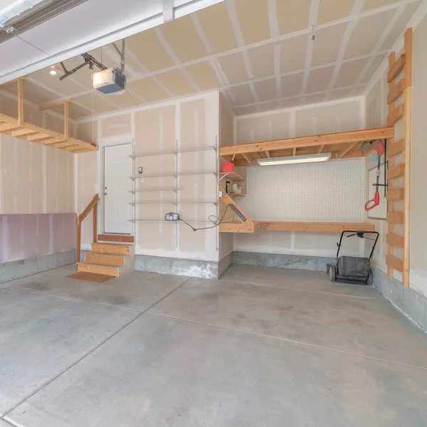 Wnętrze niewykończonego garażu z drewnianymi regałami i schodami do białych drzwi — Zdjęcie stockowe
