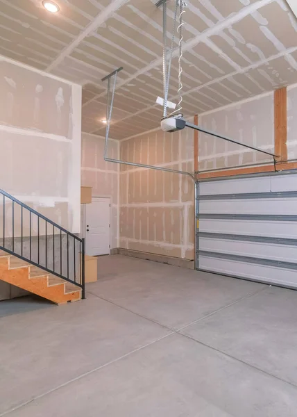 Вертикальный интерьер незаконченного гаража с автоматической белой секционной дверью — стоковое фото