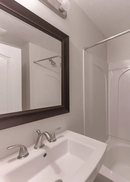Вертикальный интерьер небольшой ванной комнаты с обрамлённым зеркалом над раковиной с широко распространенным краном из нержавеющей стали — стоковое фото