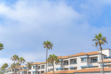 Carlsbad, San Diego, California 'da beton kiremitli çatıları olan kompleks bir binanın dışı. Gökyüzü arka planına karşı mavi pencere güneşlikleri ve parmaklıkları olan bir binanın düşük açılı görüntüsü.