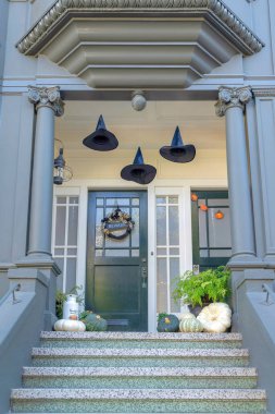 San Francisco, Kaliforniya 'da cephesinde cadılar bayramı süsleri olan bir evin verandasında. Ön kapısının yanında süslemeleri ve sütunları olan beton kapı merdivenleri olan dış giriş..