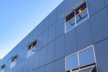 Siyah dış duvar kaplaması ve tente pencereleri olan bir binanın alçak açılı görüntüsü. Açık gökyüzüne karşı San Francisco, California 'daki modern yerleşim binası.