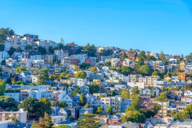 San Francisco, California 'da bir yamaçta ikamet yeri. Arkadaki açık mavi gökyüzüne bakan apartmanlar ve tek kişilik aile evleri var..