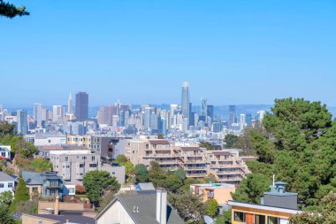 California 'daki San Francisco şehir manzarası farklı yapı tipleriyle dolu. Önde apartmanlar, arkada gökdelenler açık mavi gökyüzüne karşı..