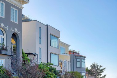 Modern ve geleneksel tasarımlı evler San Francisco, California 'da. Açık gökyüzü arka planına karşı gri ve bej rengi dış görünüşlü evler.