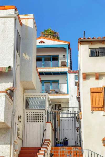 San Clemente, California 'da balkonları ve kapıları olan apartmanlar. Mahalle binaları alçak açılı, merdivenleri ön tarafta..