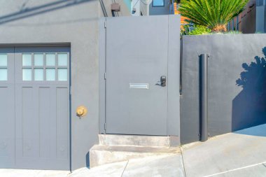 San Francisco, Kaliforniya 'da kapı kolu olan yan menteşeli bir kapı. Beton duvara bağlı kapının yanında solunda cam paneller olan bir garaj kapısı var..