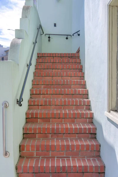 San Francisco, California 'da duvara monte edilmiş metal tırabzanlar olan kırmızı tuğlalar. Binanın dışındaki beyaz duvarların ortasındaki merdivenleri daralt..