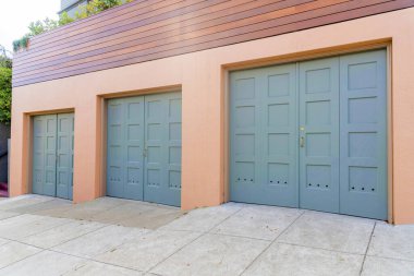 San Francisco, California 'da altın kapı kollu üç yan menteşeli garaj kapısı. Ahşap çitin altında, üzerinde bitkiler olan bir garaj..