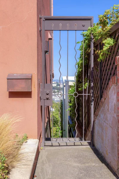 San Francisco, California 'da duvarında posta kutusu olan tek bir metal kapı. Girişte solda çimenler ve sağda ahşap çitler var..