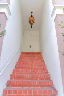 San Francisco, Kaliforniya 'da kırmızı tuğlalar ve kolye ışığı. Beyaz duvarların ortasındaki merdivenler üst taraftaki beyaz ön kapıya gidiyor..