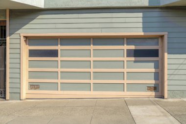 San Francisco, Kaliforniya 'da yeşilimsi gri tonlarla kaplanmış bir garaj. Beton bloknotlu garaj ve sol taraftaki işlenmiş demir kapının yanında bej kapılı bölüm kapısı..