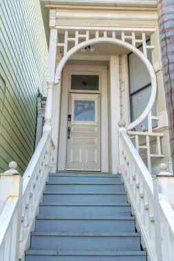 San Francisco, California 'da beyaz tırabzanlı ahşap kapılar. Süslü parmaklıkları ve pencere paneli ve kapı kamerası olan beyaz kapılı bir evin verandası..