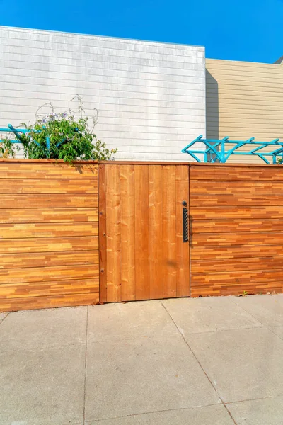 Tahta duvar çitleri ve Kaliforniya, San Francisco 'daki kapı. Ahşap kapının önünde tahta kaplamalı, tahta kaplamalı ve asmalı ağaç çatılı binalara karşı beton levhalar var..