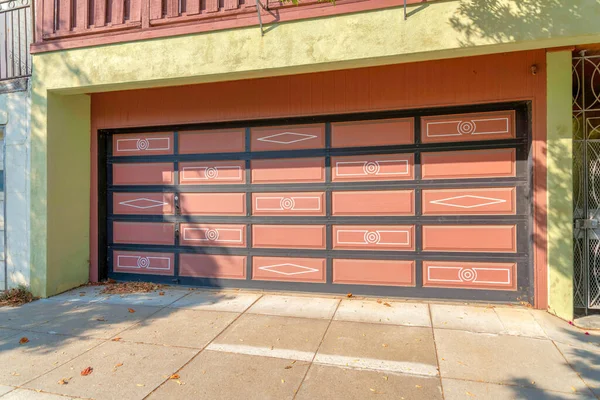 San Francisco, Kaliforniya 'da şeftali kaplamalı ve siyah ızgaralı bir garaj. Panellerde beyaz semboller ve kuru yapraklı beton garaj kapısı..