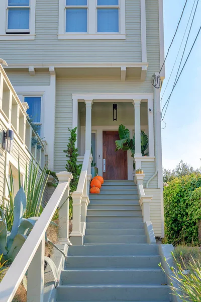 Merdivenler San Francisco, California 'da gri basamaklı bir evin girişinde. Çiçeklerin ortasında parmaklıkları olan merdivenler yan taraftaki bitkilerle ahşap kapıya çıkıyor..