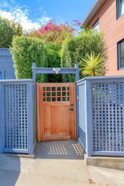 San Francisco, Kaliforniya 'da açık mavi ahşap çitli ahşap kapı. Çalı çalılarına ve arkadaki binaya karşı bir kapı var..