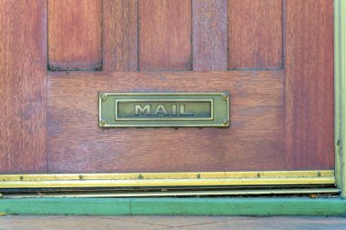 San Francisco, California 'da ahşap bir kapıdaki posta kutusu. Altında çivilenmiş altın çerçevelerin yanındaki ahşap kapının altında, önünde postalar olan metal posta kutusu..