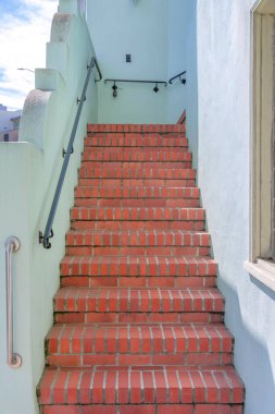 San Francisco, California 'da duvara monte edilmiş metal tırabzanlar olan kırmızı tuğlalar. Binanın dışındaki beyaz duvarların ortasındaki merdivenleri daralt..