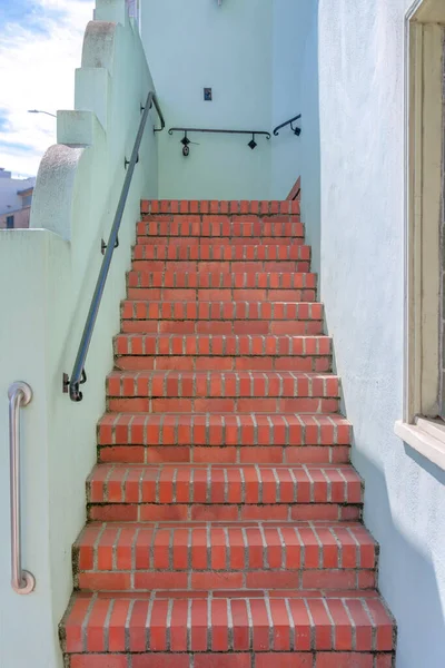 San Francisco, California 'da duvara monte edilmiş metal tırabzanlar olan kırmızı tuğlalar. Binanın dışındaki beyaz duvarların ortasındaki merdivenleri daralt..