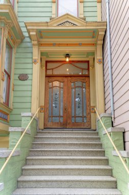 Kasaba girişinde beton kapı merdivenleri ve büyük ahşap çift kapı var. San Francisco ikametgahı, Kaliforniya 'da, ahşap yeşil kaplamalı, sarı ve turuncu çerçeveli..
