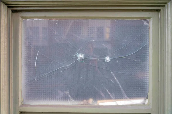 Framed window with crack on the glass at San Francisco, California. Close up of a window pane with gray frame and cracked reflective glass pane.