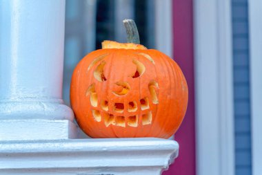 San Francisco, California 'da bir evin önünde oyulmuş balkabağı Cadılar Bayramı dekoru. Sütun direğinin yanındaki tırabzanın tepesinde bir balkabağının yakın çekimi.