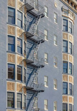 Dışarıdaki apartmanda gri duvar ve metal acil durum merdivenleri var. Süslü süslemeleri ve tasarımları olan San Francisco, California 'daki konut binası..