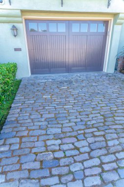 San Francisco, California 'daki bir garajın taş blokları. Garajın dış tarafında pencere panelleri ve sol tarafında lamba olan yan menteşeli siyah garaj kapıları olan bir ev..