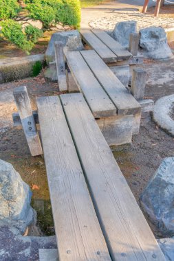 San Jose, Kaliforniya 'daki Japon Dostluk Bahçesi' nde çapraz ahşap köprüler. Çamurlu bir yatağın üzerinde, köprünün sonunda küçük ağacın yanında büyük kayalar olan kısa, ahşap bir köprü..