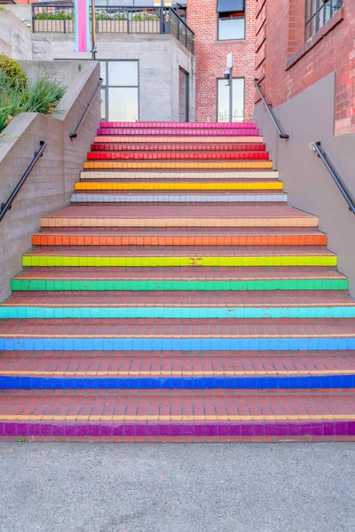 Colorful outdoor stairs near the Fisherman's Wharf in San Francisco, California. Bricks stairs with painted risers and wall-mounted handrail leading to the buildings with brick wall at the background.