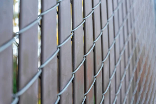 Selective focus of a chain link fence with brown privacy strips at Japanese Friendship Garden. Close-up of a fence with blurred background in San Jose, California.