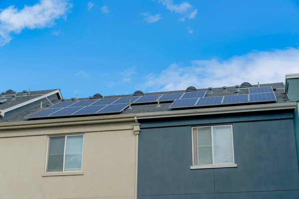 Building with solar panels on the roof at Silicon Valley, San Jose, CA. Building exterior with beige on the left and dark gray on the right against the sky at the back.