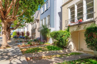 San Francisco, California 'da garajı olan mahalledeki evler. Garaj kapısının önünde kaldırıma bağlı beton yolların yanında çalılıklar var..