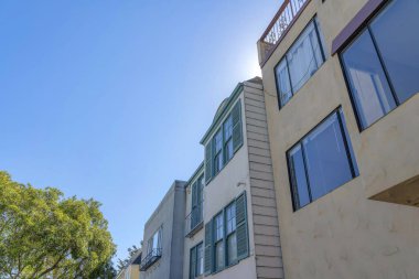 San Francisco, California 'daki kompleks konut binalarının alçak açılı görüntüsü. Soldan iki bina var. Penceresinde parmaklıklar var. Sağında da resim pencereli bir bina..