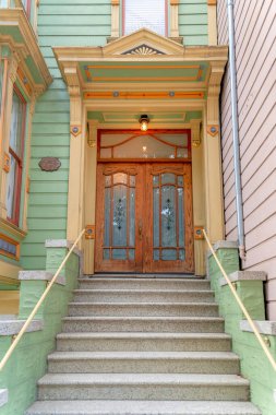 Kasaba girişinde beton kapı merdivenleri ve büyük ahşap çift kapı var. San Francisco ikametgahı, Kaliforniya 'da, ahşap yeşil kaplamalı, sarı ve turuncu çerçeveli..