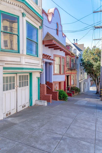 San Francisco, California 'da eğimli bir bölgede sıra sıra evler. Eğimli beton kaldırımlı ve renkli dış binalı yerleşim alanı..