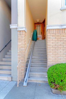 Ahşap ön kapıya çıkan beton merdivenlerde merdiven yükselticisi olan bir evin ön girişi. Sağında tuğla ve bitkiler olan San Francisco, California 'da bir evin dışında..