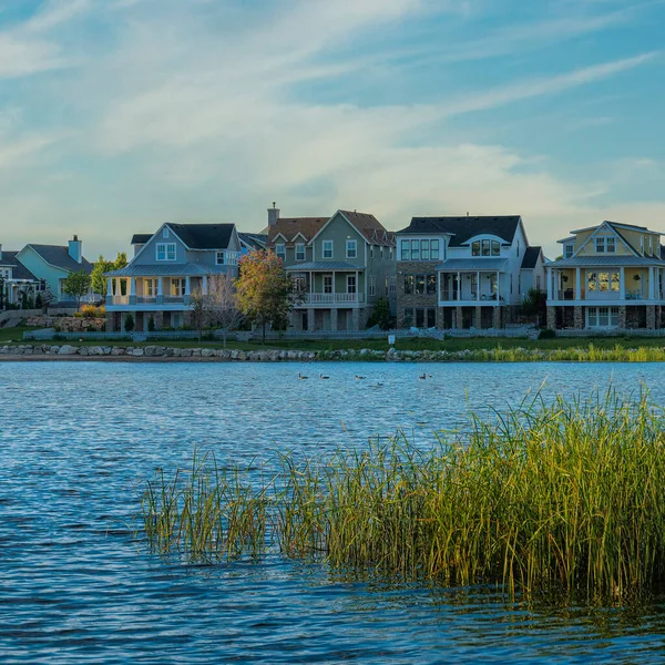 Kare Whispy beyaz bulutları Oquirrh Gölü kıyısı Daybreak, Utah 'ta gün batımında. Sol tarafta kapalı bir rıhtım ve arka planda gökyüzü ufkuna ve dağa karşı büyük evler var..