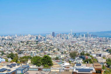 San Francisco, California 'daki binaların yüksek açılı manzarası. Cephede bir çatı katı manzarası var. Güneş panelleri, kasabanın manzarasına ve körfez yakınlarındaki gökdelen binalarına karşı..
