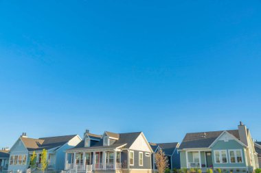 Houses at Daybreak in South Jordan, Utah with asphalt shingle roofs and colorful vinyl wood sidings. Facade of houses with railings at the porch doorsteps against the sky background.