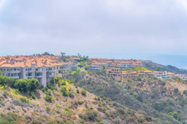 Apartment buildings on a mountain area of Laguna Niguel in California. Residential area on top of a mountain slope with trees and shrubs against the sky.